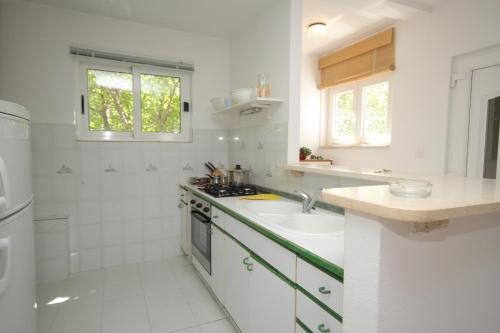 a white kitchen with a sink and a shower at Apartments by the sea Baska Voda, Makarska - 6848 in Baška Voda