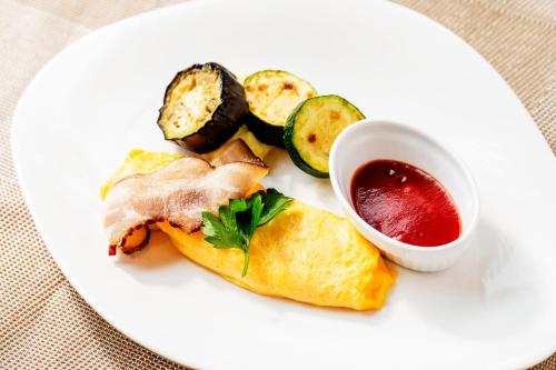 a white plate with a sandwich and a cup of sauce at Garden Terrace Fukuoka in Fukuoka