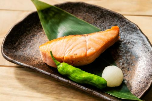 a plate with a piece of fish and a green pepper at Garden Terrace Fukuoka in Fukuoka