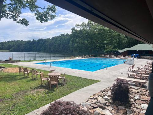 a swimming pool with tables and chairs next to a lake at Centrally Located Resort in The High Country RELAX in Newland