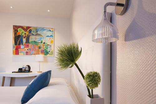 a bedroom with a bed with a potted plant and a lamp at Hôtel Escale Oceania Lorient in Lorient
