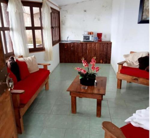 ein Wohnzimmer mit einem roten Sofa und einem Tisch mit Blumen in der Unterkunft Cabañas Campestre Sierra Viva in Zacatlán