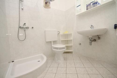 a white bathroom with a toilet and a sink at Apartments by the sea Starigrad, Paklenica - 6586 in Starigrad