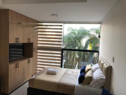 a bedroom with a bed and a large window at Stanza Equipetrol in Santa Cruz de la Sierra