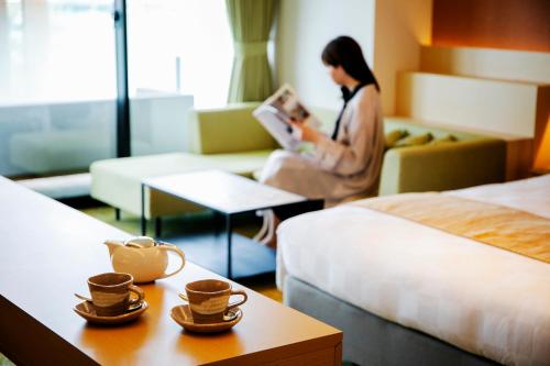 a woman reading a book in a hotel room at Garden Terrace Fukuoka in Fukuoka