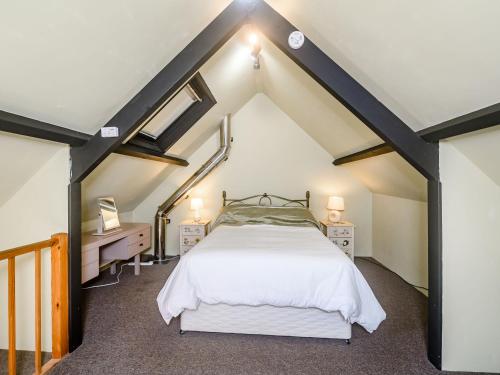 ein großes Schlafzimmer im Dachgeschoss mit einem Bett und einem Schreibtisch in der Unterkunft Creenagh's Cottage in Withypool