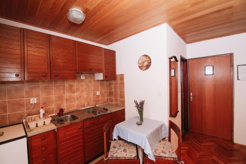 a kitchen with wooden cabinets and a table in it at Apartments and rooms with parking space Novalja, Pag - 6482 in Novalja