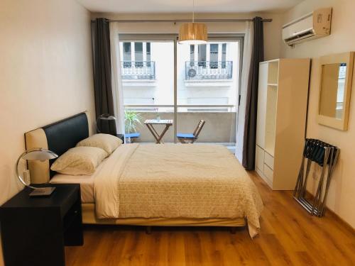 a bedroom with a bed and a large window at Apartamento Céntrico y Moderno con Balcon, Piscina, Gimnasio y Laundry in Buenos Aires