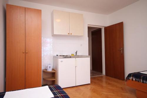 a small kitchen with a white cabinet and a bed at Apartments and rooms with parking space Podgora, Makarska - 6790 in Podgora