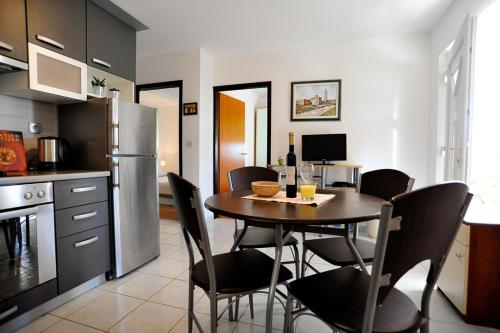 La cuisine est équipée d'une table, de chaises et d'un réfrigérateur. dans l'établissement Apartments with a parking space Sukosan, Zadar - 6131, à Sukošan