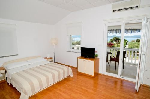 - une chambre avec un lit, une télévision et un balcon dans l'établissement Apartments with a parking space Sukosan, Zadar - 6131, à Sukošan