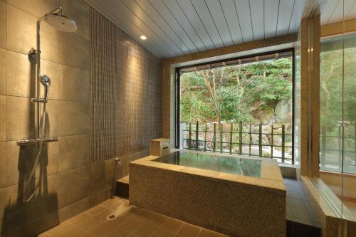 a bathroom with a tub and a large window at Arima Onsen Taketoritei Maruyama in Kobe