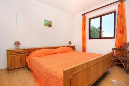 a bedroom with a bed with an orange bedspread and a window at Secluded fisherman's cottage Cove Suha Punta, Kornati - 8168 in Pinizelić