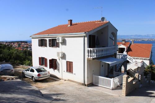 a white house with a car parked in front of it at Apartments by the sea Kali, Ugljan - 8202 in Kali