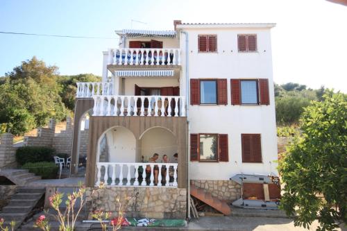 a building with a balcony with people on it at Apartments by the sea Kali, Ugljan - 8202 in Kali