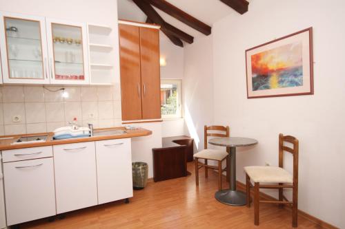 uma cozinha com armários brancos e uma mesa e cadeiras em Apartments by the sea Bilo, Primosten - 8364 em Primošten
