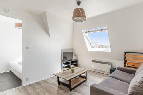 un salon avec un canapé et une table dans l'établissement Appartement Risco - Welkeys, à Villers-sur-Mer