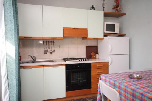 a kitchen with white cabinets and a stove and a refrigerator at Apartments by the sea Skrivena Luka, Lastovo - 8352 in Lastovo