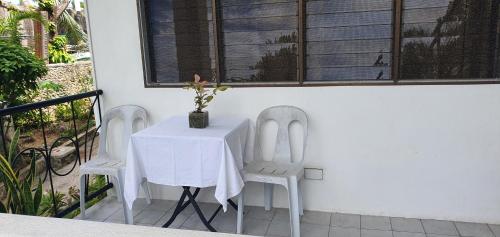 麥克坦的住宿－Lola's Guest House，一张带两把椅子的白色桌子和一张带花瓶的桌子