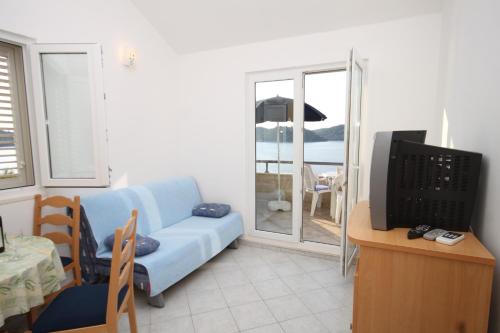 ein Wohnzimmer mit einem blauen Sofa und einem TV in der Unterkunft Apartments by the sea Ubli, Lastovo - 8355 in Ubli