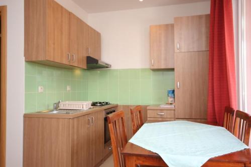 a kitchen with wooden cabinets and a table and a sink at Apartments by the sea Pasman - 8217 in Pašman