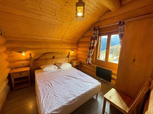 une chambre avec un lit dans une cabane en rondins dans l'établissement Chalet en rondin 8 pers. avec sauna, SPA et garage, près télécabine et navette à Praloup 1500 - FR-1-165A-126, à Uvernet