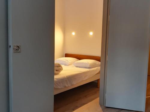 une chambre avec un lit avec des draps blancs et des oreillers dans l'établissement Appartement avec parking, lave-linge et proche bus de Genève et domaines skiables - FR-1-517-62, à Chamonix-Mont-Blanc