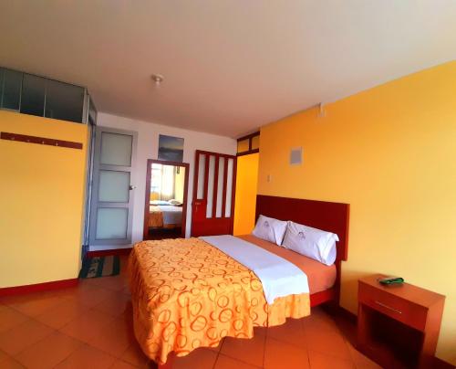 a bedroom with a large bed with yellow walls at Hospedaje Las Lilas in Huancayo