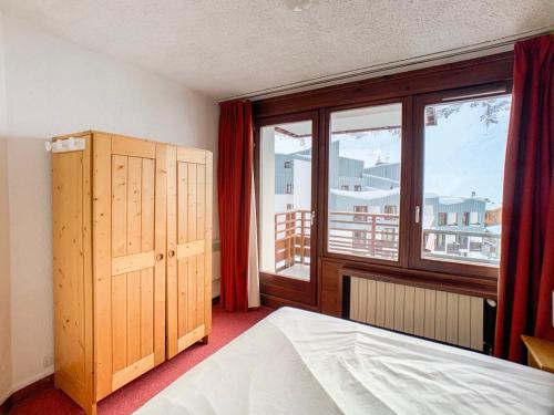 une chambre avec un lit et une grande fenêtre dans l'établissement Appartement lumineux 3 pièces, skis aux pieds, 10 pers, balcon, proche commerces et pistes - FR-1-502-362, à Tignes
