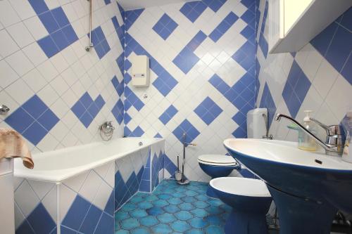 a blue and white bathroom with a toilet and a sink at Apartments by the sea Kastel Stafilic, Kastela - 8621 in Kaštela