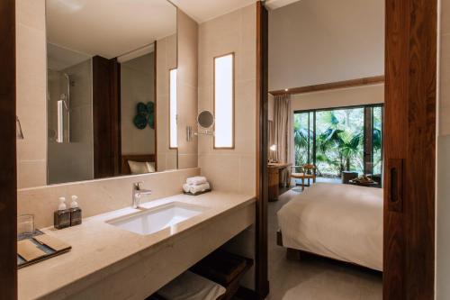 a bathroom with a sink and a bed at Dusit Princess Moonrise Beach Resort in Phu Quoc