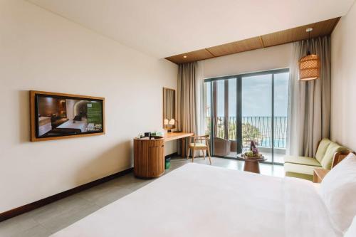a bedroom with a large bed and a large window at Dusit Princess Moonrise Beach Resort in Phu Quoc