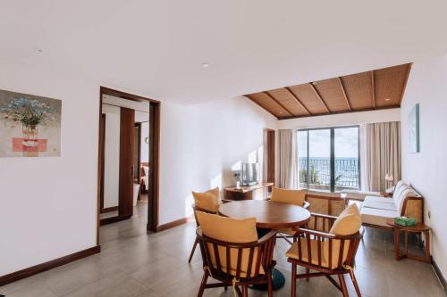 a living room with a wooden table and chairs at Dusit Princess Moonrise Beach Resort in Phu Quoc