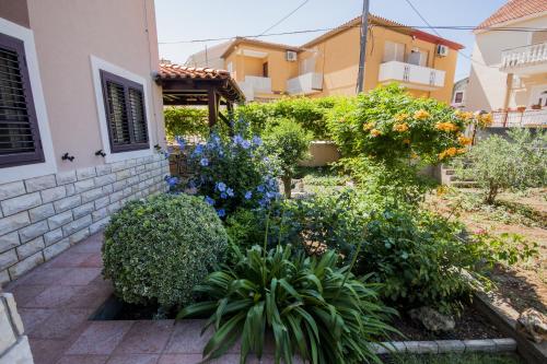 a garden in front of a house with flowers and plants at Apartments by the sea Kukljica, Ugljan - 8253 in Kukljica