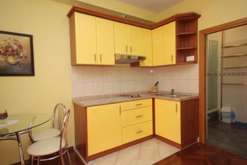 a small kitchen with yellow cabinets and a table at Apartments by the sea Kukljica, Ugljan - 8253 in Kukljica