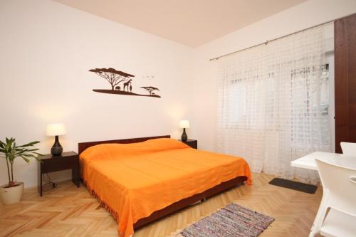 a bedroom with a bed with an orange bedspread at Apartments by the sea Duce, Omis - 8633 in Omiš