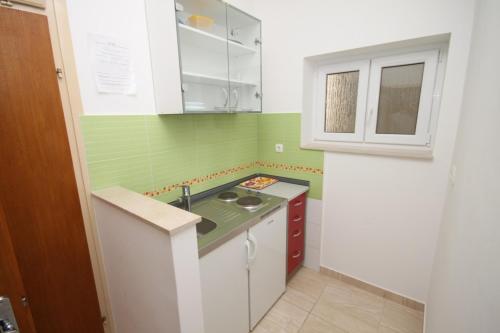 a small kitchen with green and white cabinets and a sink at Apartments by the sea Duce, Omis - 8633 in Omiš