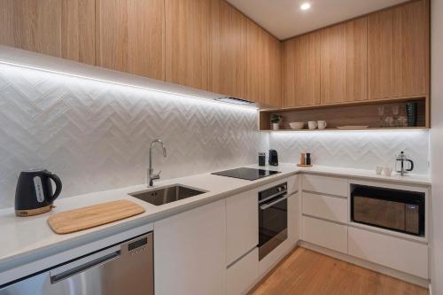 una cucina con mobili bianchi e un lavandino di Malthouse Lane City Apartment 2 a Nelson
