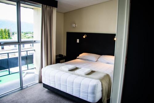 a bedroom with a bed and a large window at Fiordland Hotel in Te Anau