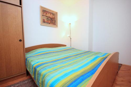 薩利的住宿－Apartments by the sea Sali, Dugi otok - 8194，一张床上,床上有一条色彩缤纷的条纹毯子