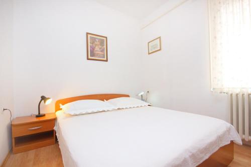 a bedroom with a white bed and a wooden nightstand at Apartments by the sea Sali, Dugi otok - 8193 in Sali