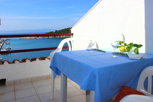 a blue table with wine glasses and a view of the water at Apartments and rooms by the sea Zaklopatica, Lastovo - 8339 in Lastovo