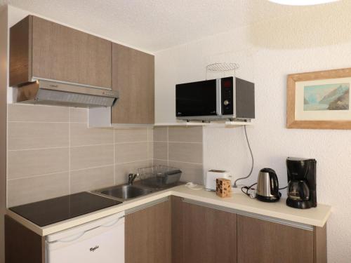une petite cuisine avec un évier et un micro-ondes dans l'établissement Studio rénové avec balcon aux pieds des pistes, WiFi, animaux permis - FR-1-502-415, à Tignes