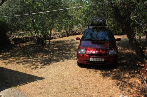 a red car parked in the shade of a tree at Apartments by the sea Zdrelac, Pasman - 8299 in Ždrelac