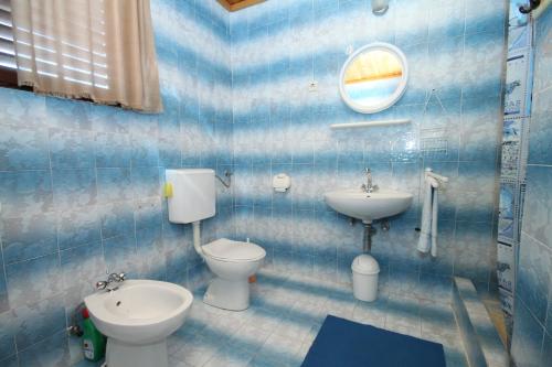 Baño de azulejos azules con aseo y lavamanos en Apartments with a parking space Kraj, Pasman - 8372 en Tkon