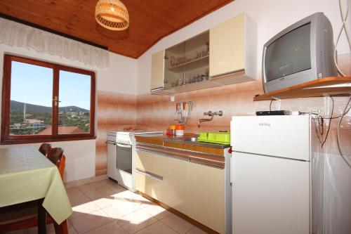 a kitchen with a white refrigerator and a tv on the wall at Apartments by the sea Lukoran (Ugljan) - 8475 in Lukoran