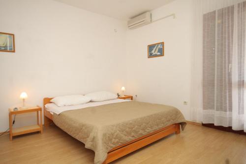 a white bedroom with a bed and two night stands at Apartments and rooms by the sea Mrljane, Pasman - 8464 in Neviđane