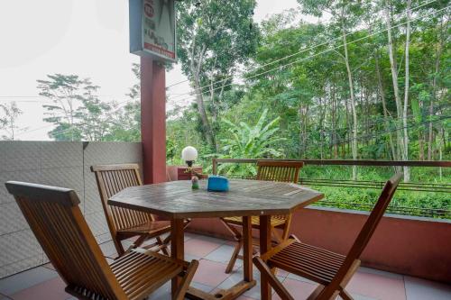 a table and chairs on a balcony with a view of trees at Urbanview Hotel Bergas Indah Bandungan by RedDoorz in Bandungan