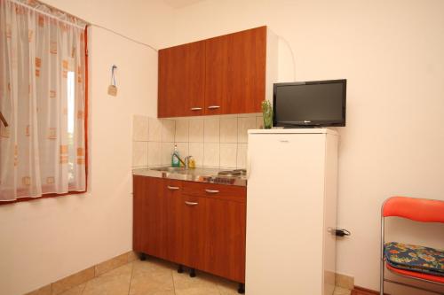 a kitchen with a refrigerator and a tv on the wall at Studio Susica 8265a in Ugljan