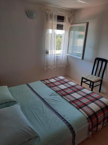 a bed in a room with a chair and a window at Apartments and rooms with parking space Susica, Ugljan - 8265 in Ugljan